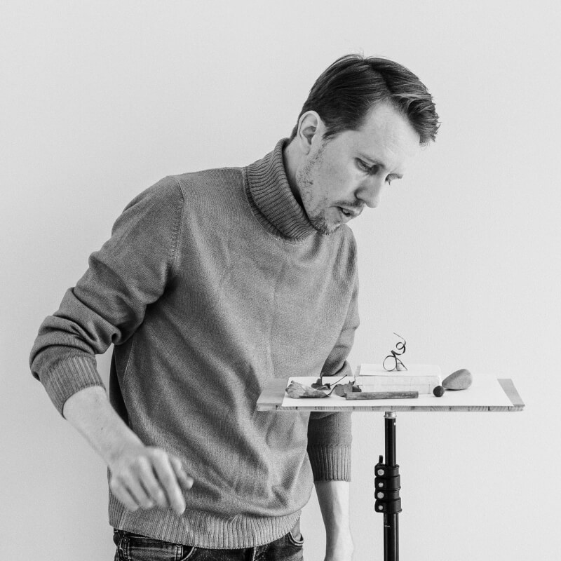 Photo in black and white of photographer Christian Svinddal arranging a still life composition