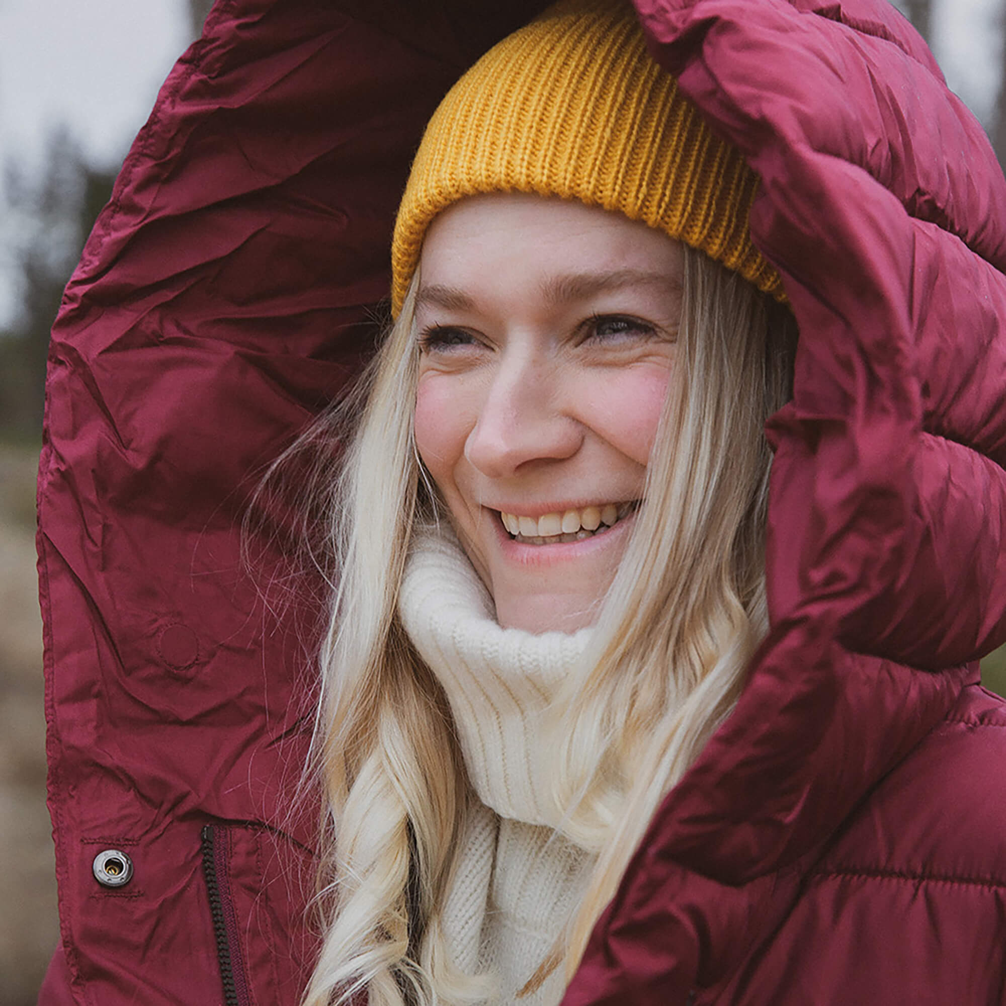 A portrait of photographer Isabella Ståhl in a yellow beanie and red jacked