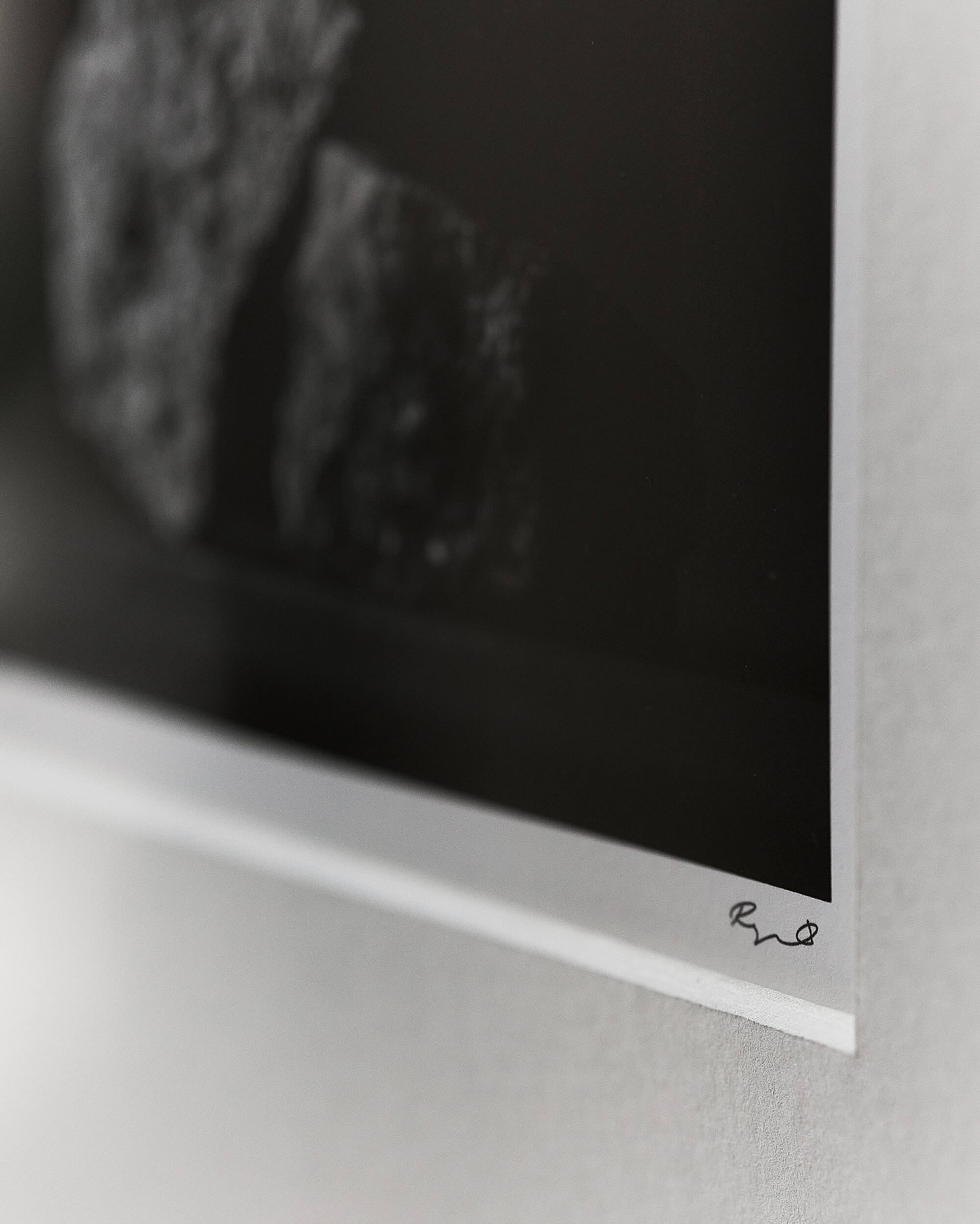 A close-up of a black and white art print with a signature, mounted on a passepartout
