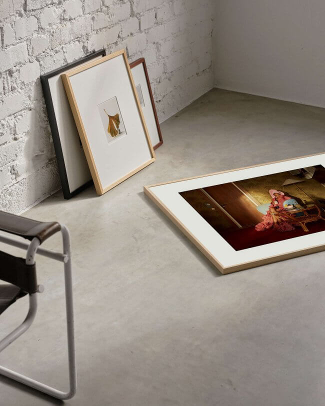 Limited edition art print in color laying on a concrete floor, framed in an oak frame